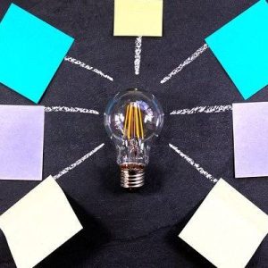 A lightbulb with a dark grey back ground with post it notes surrounding